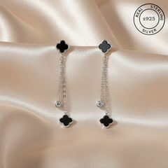 Pair of silver earrings with black clover-like designs  featuring 'Real Sterling Silver' certification.
