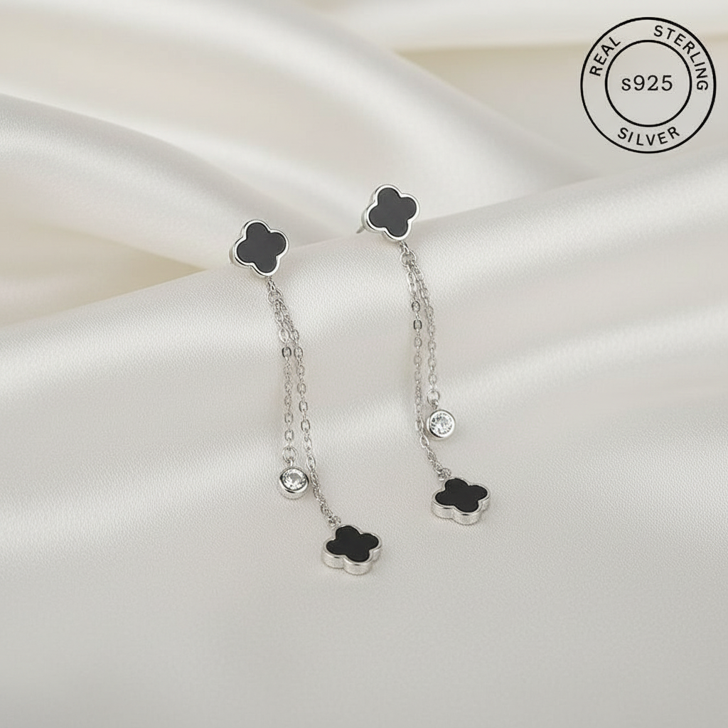 Silver earrings with black clover-shaped tops featuring 'Real Sterling Silver' label.