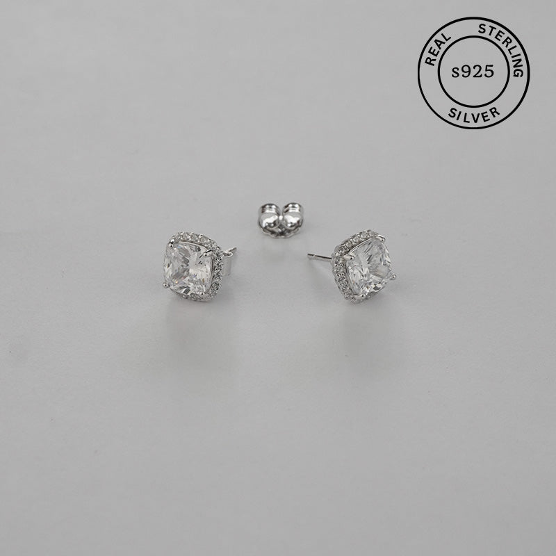 Pair of silver stud earrings on a gray background with 'Real Sterling Silver' stamp.