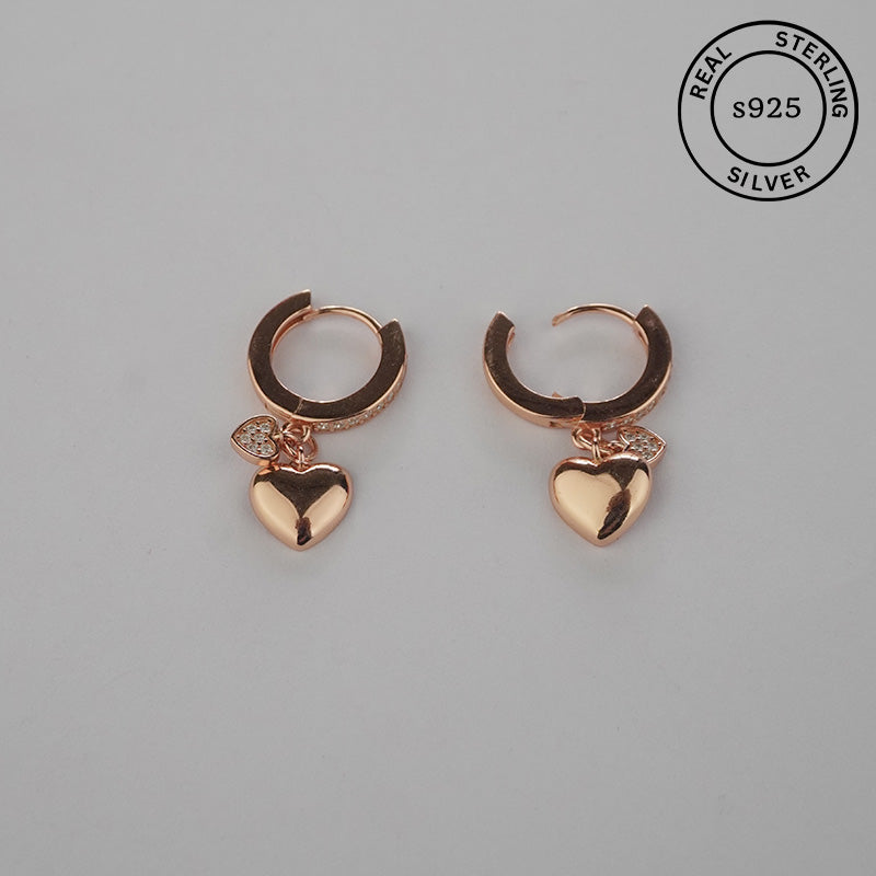 Rose gold hoop earrings with heart charms with a 'Real Sterling Silver' stamp.