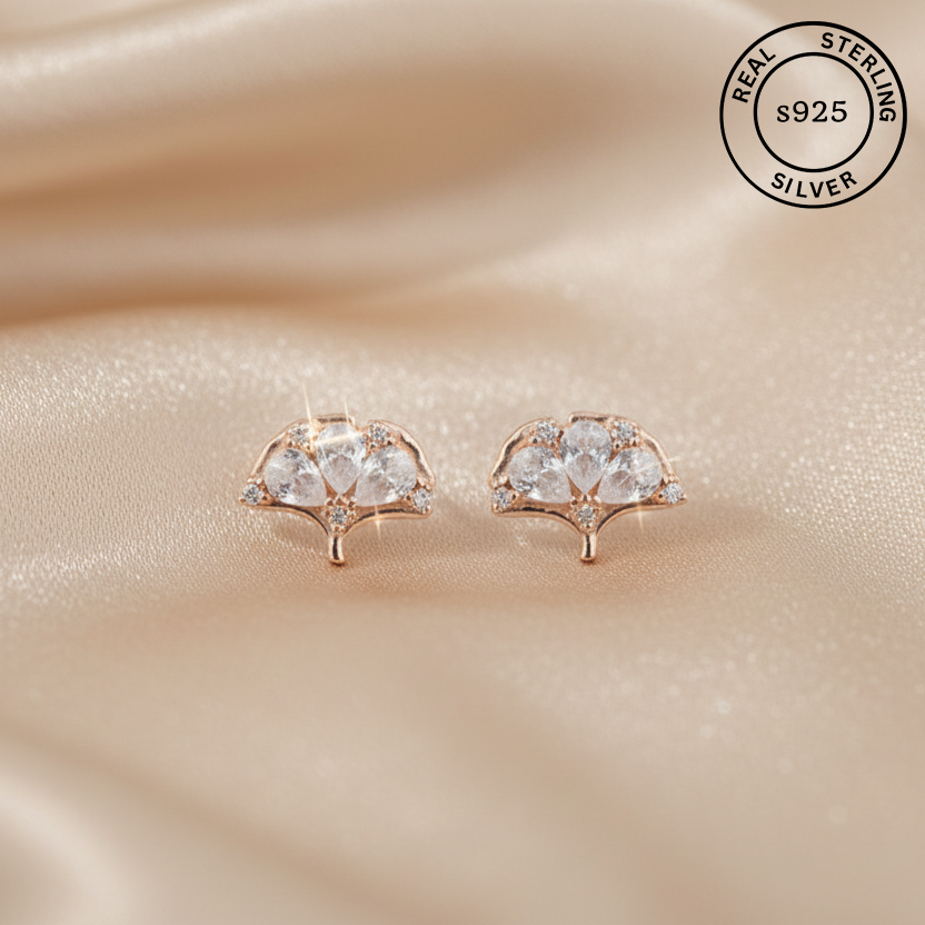Rose gold earrings with AAA+ CZ on a beige fabric background, featuring 'Real Sterling Silver 925' label.