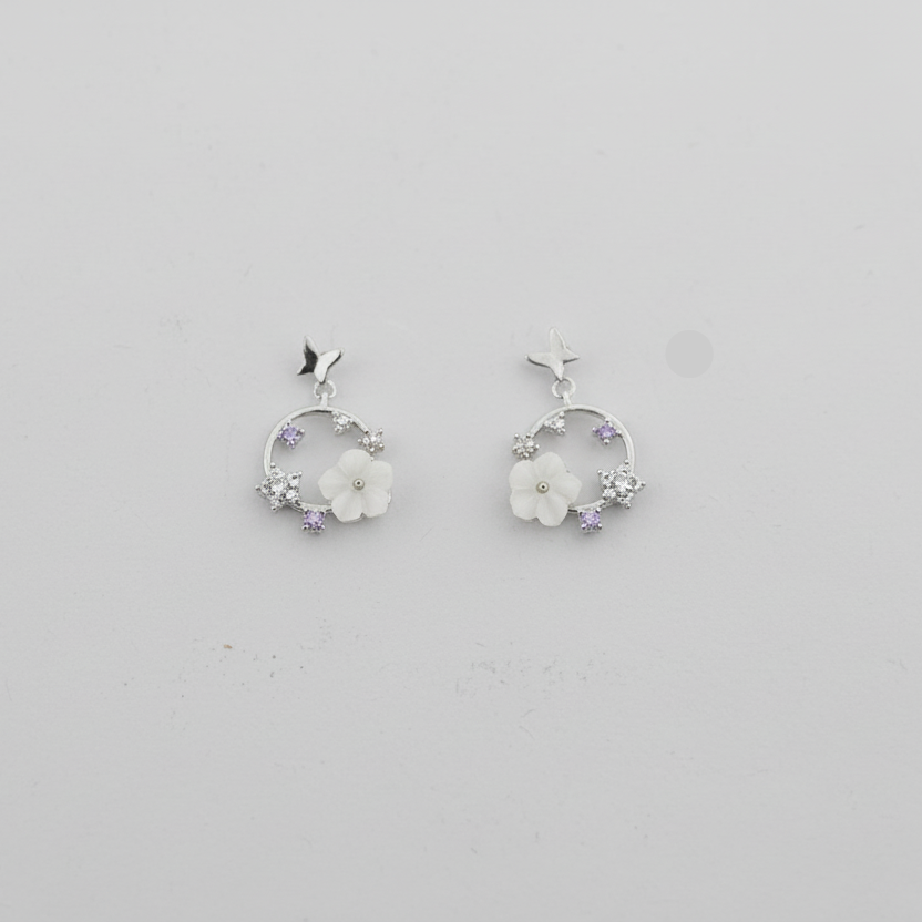 Pair of silver hoop earrings with floral designs on a light gray background