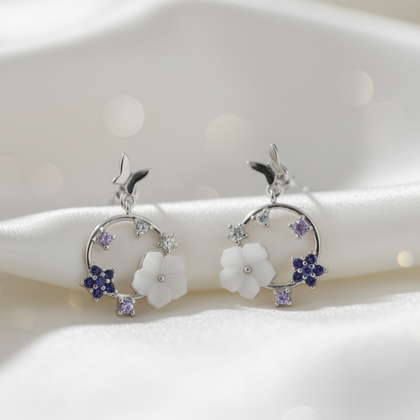 Pair of silver earrings with floral designs on a white background
