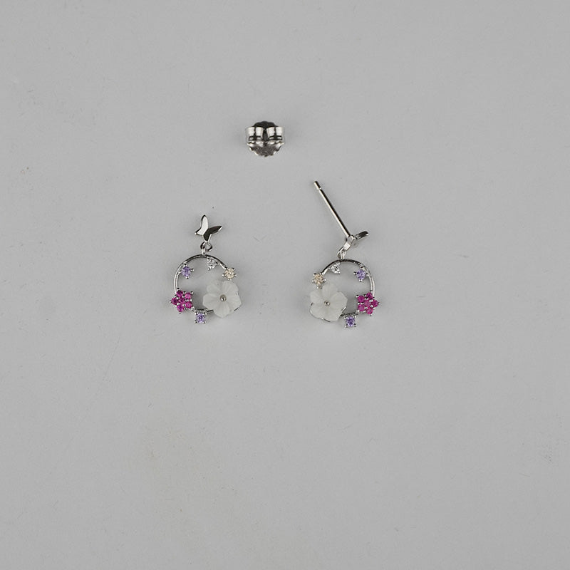 Pair of silver earrings with floral designs on a gray background