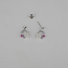 Pair of silver earrings with floral designs on a gray background