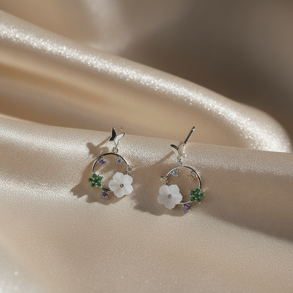 Silver earrings with floral designs on a beige fabric background