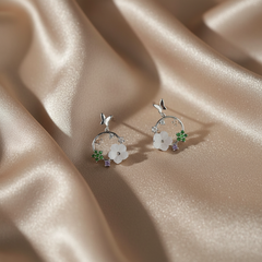 Silver earrings with floral designs on a beige fabric background