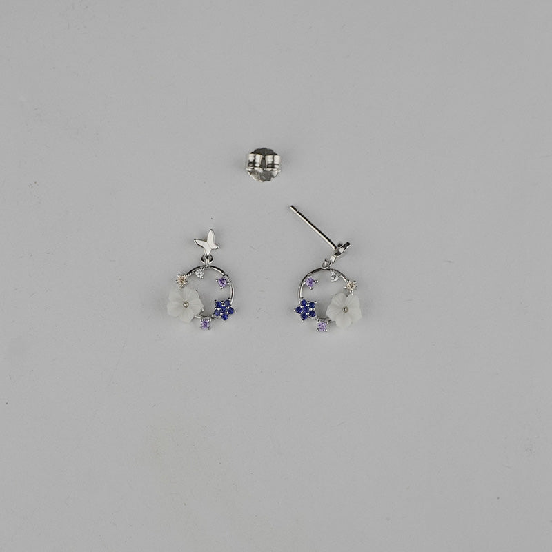 Silver earrings with floral designs on a gray background