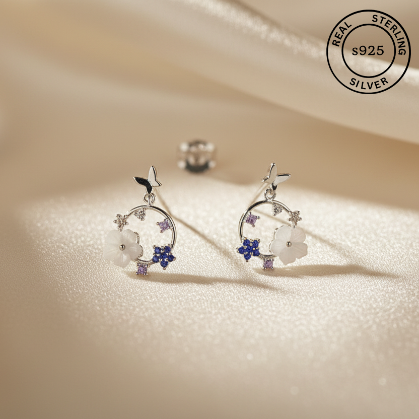 Silver earrings with floral design on a beige background, featuring 'Real Sterling Silver' 925 stamp.