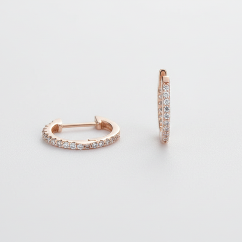 Rose gold hoop earrings with embedded stones on a light gray background