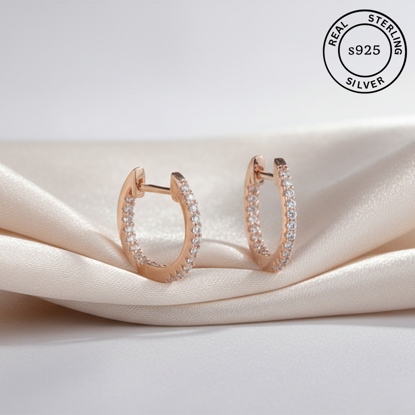 Rose gold hoop earrings with AAA+ CZ  on a beige fabric background, featuring 'Real Sterling Silver 925' stamp.