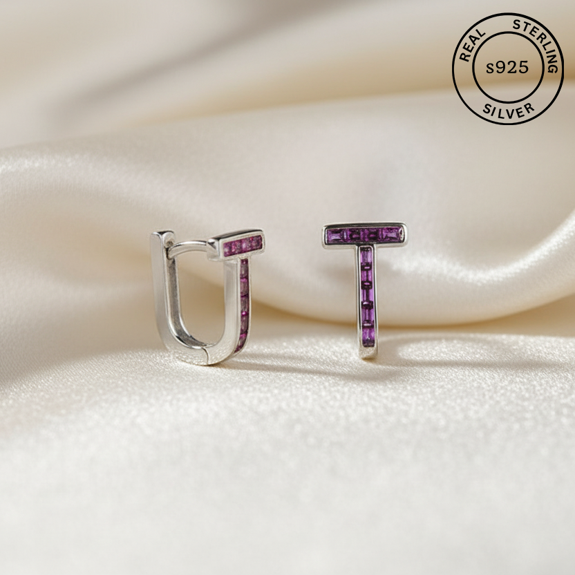Silver earrings with purple gemstones on a white fabric background, featuring 'Real Sterling Silver s925' label.