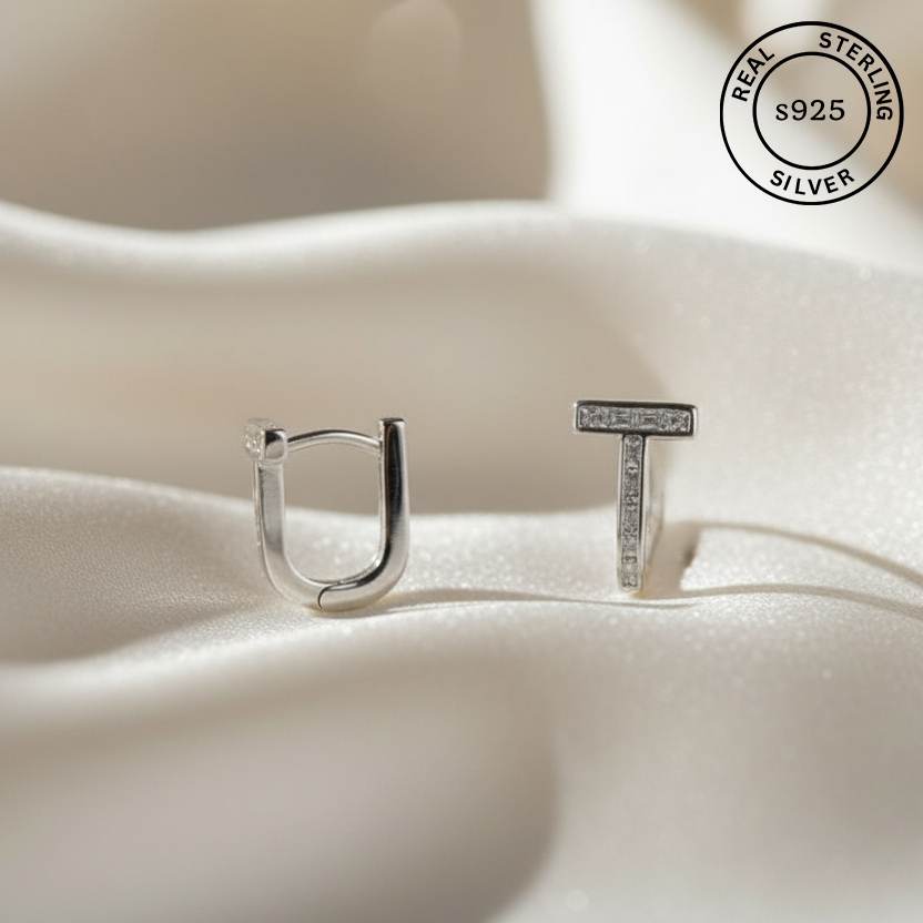 Silver earrings with 'UT' on a soft fabric background, featuring a 'Real Sterling Silver' stamp.