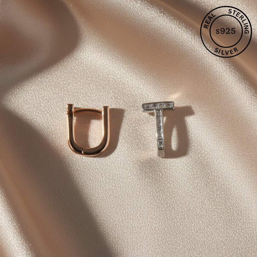 Gold 'U' and silver 'T' earrings on a beige fabric background with 'Real Sterling Silver 925' stamp.