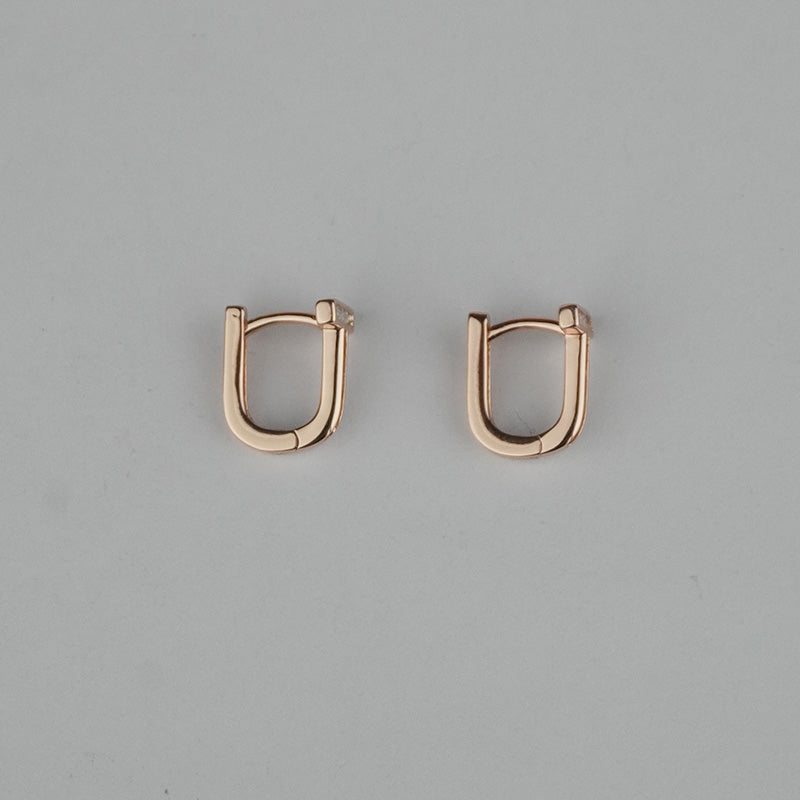 Pair of rose gold hoop earrings on a gray background