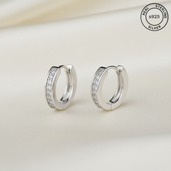 Silver hoop earrings with embedded stones on a light background, featuring 'Real Sterling Silver' label.