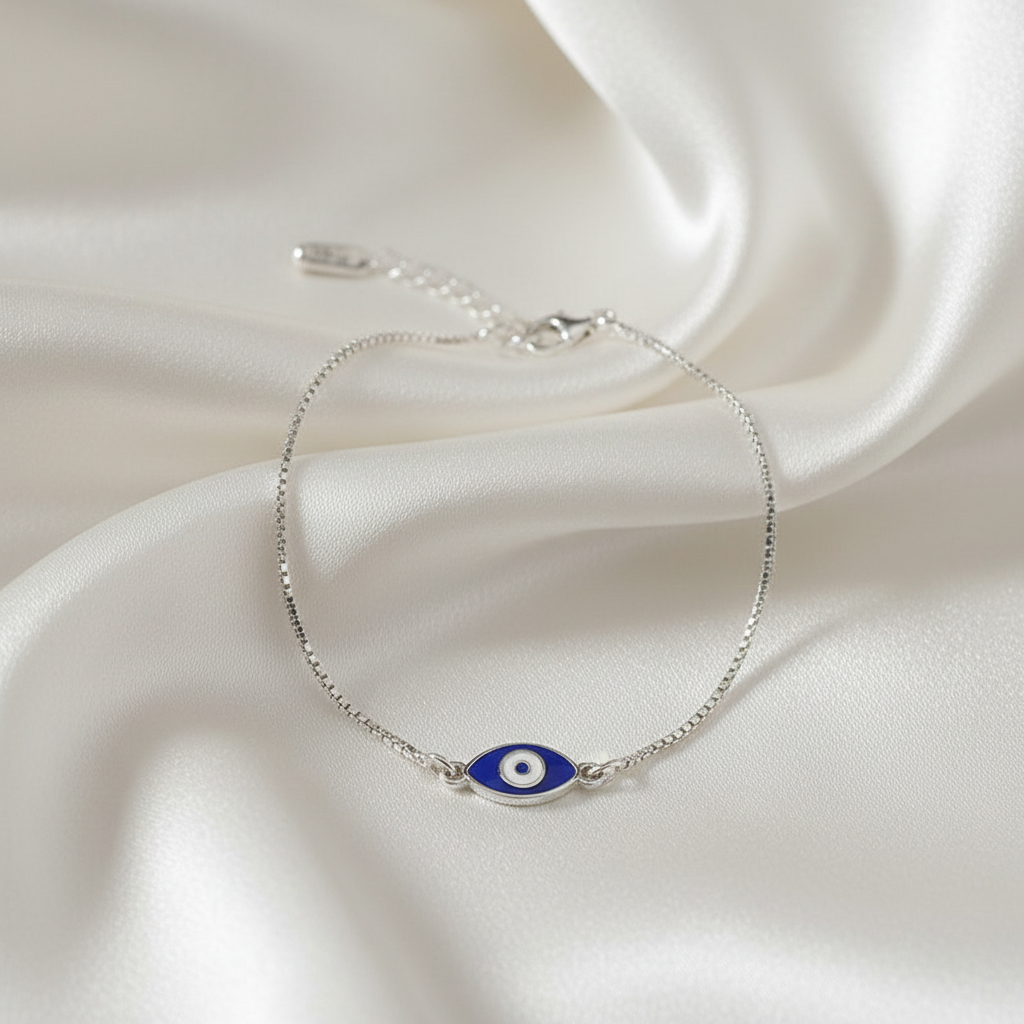 Silver bracelet with a blue evil eye charm on a white fabric background