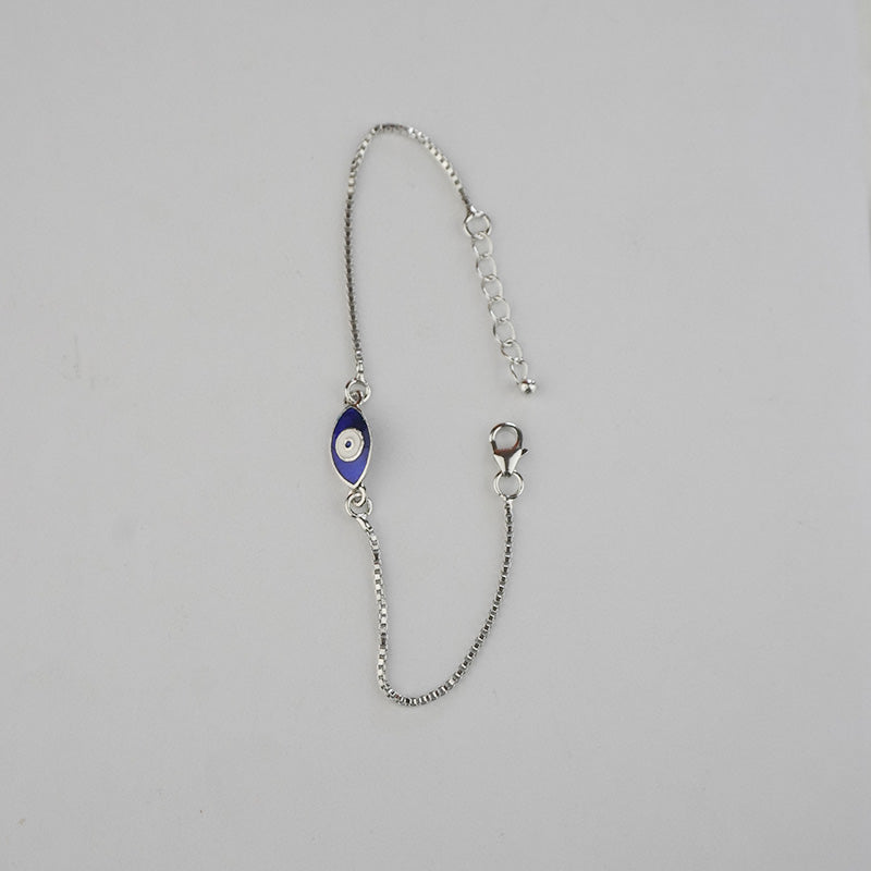 Silver bracelet with a blue evil eye charm on a gray background