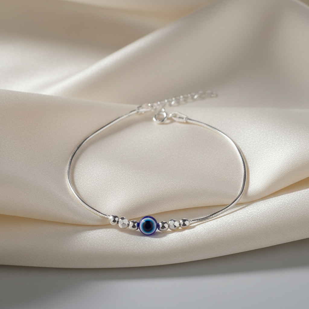Silver bracelet with a blue evil eye bead on a beige fabric background