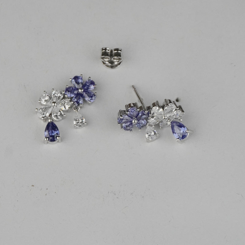 Pair of silver earrings with purple gemstones on a gray background