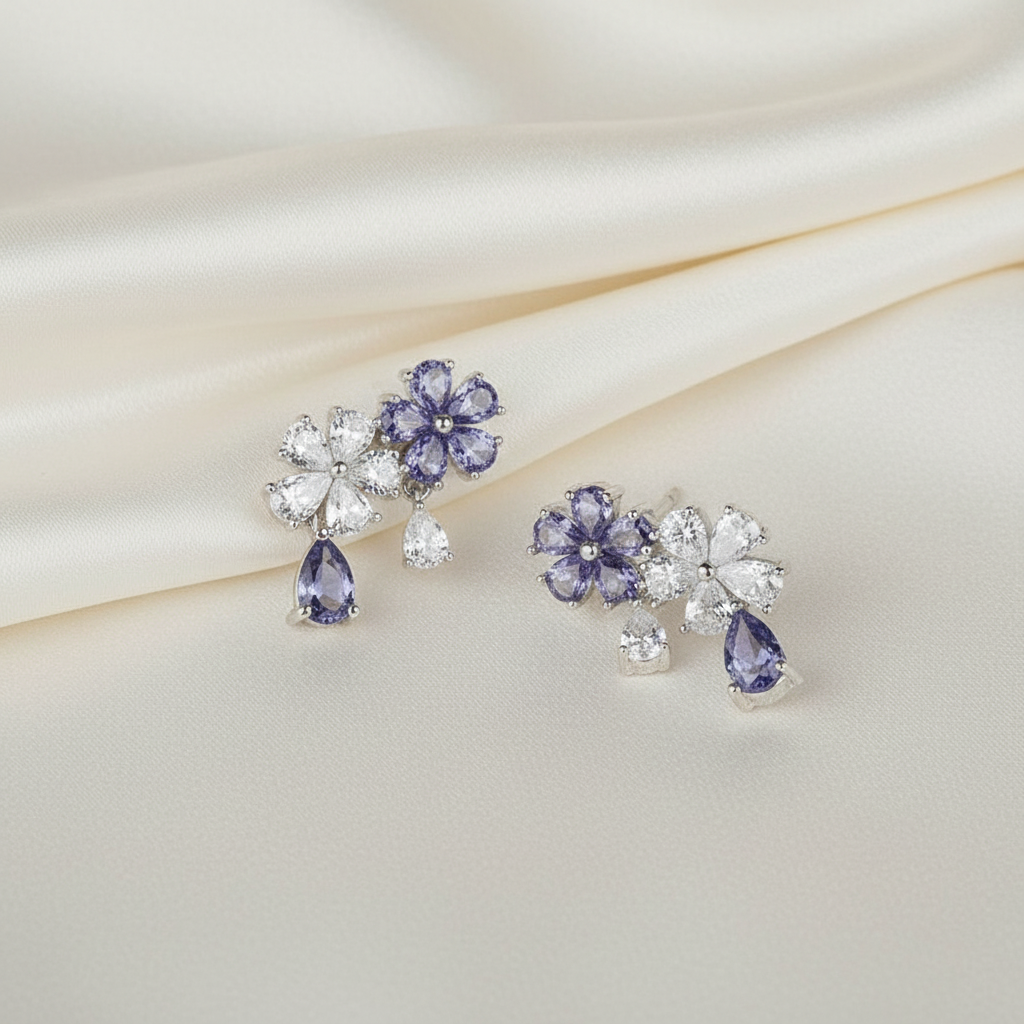 Pair of floral earrings with purple gemstones on a soft fabric background