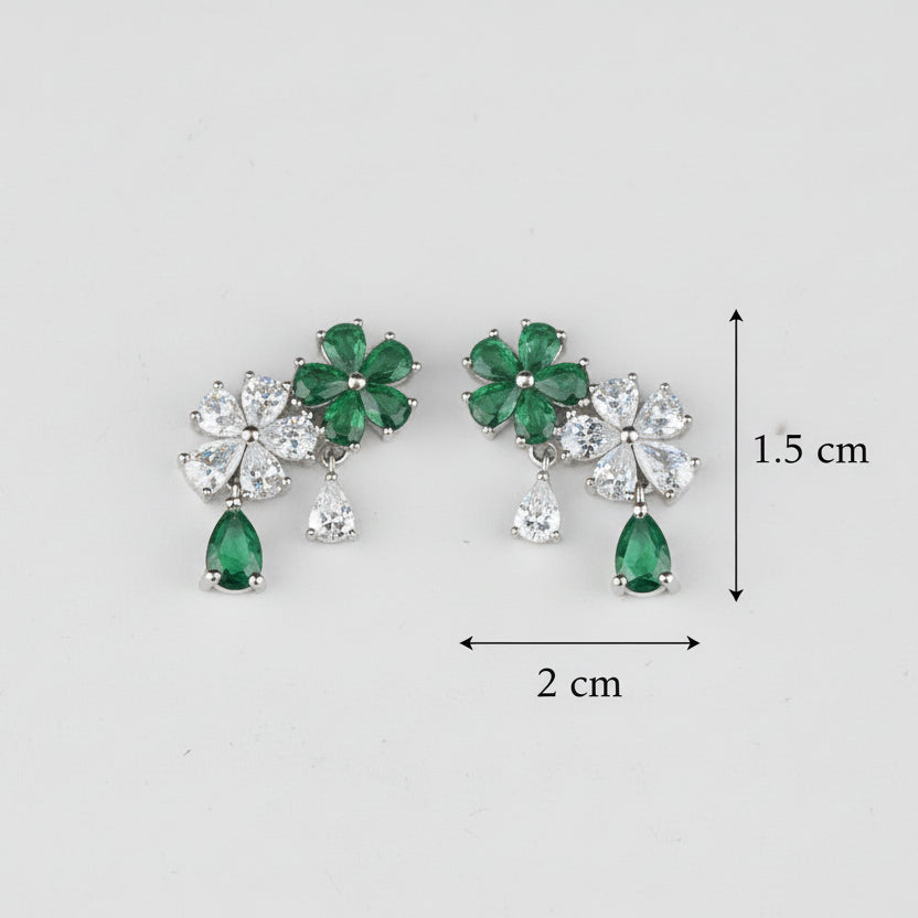 Pair of earrings with green gemstones and clear stones on a light gray background