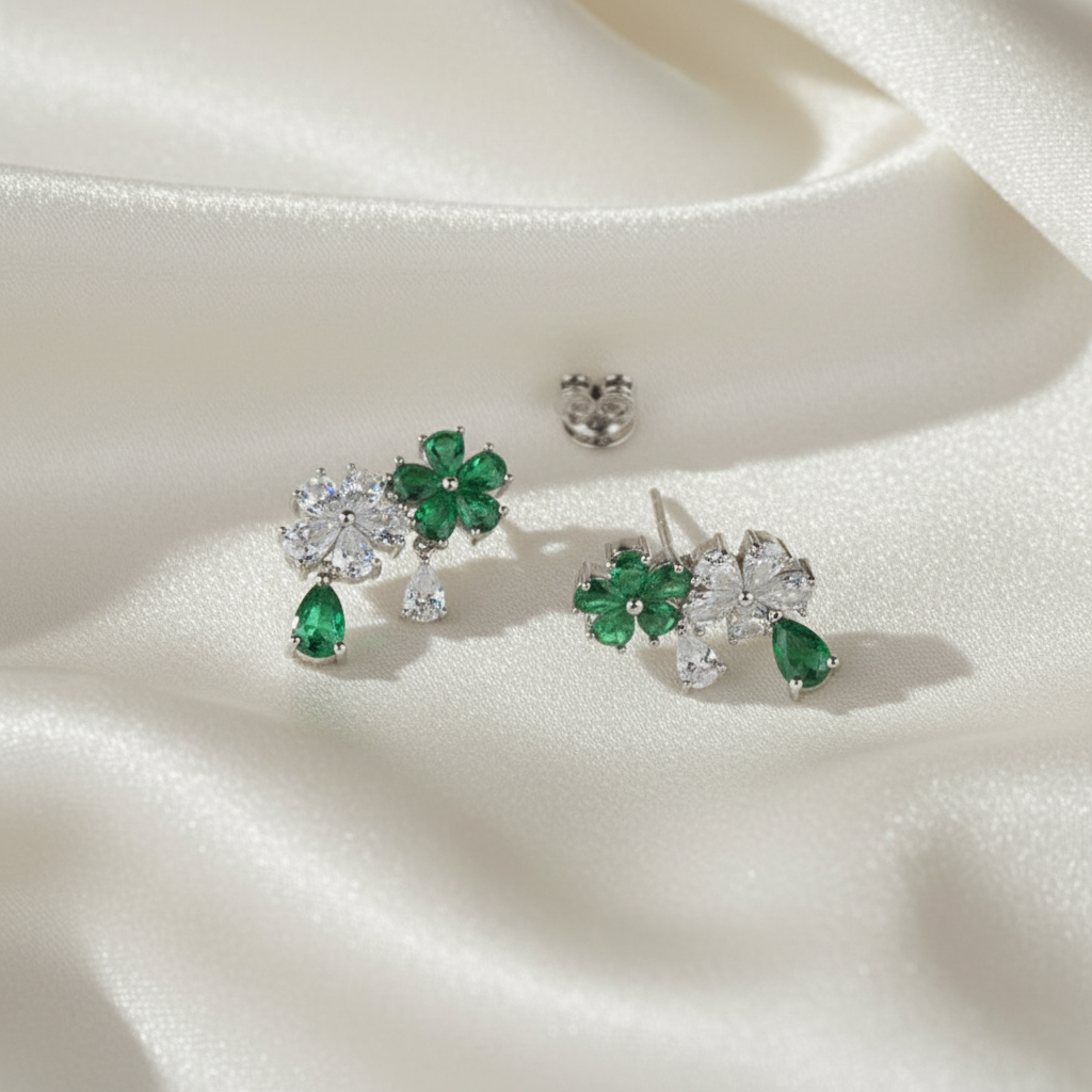 Pair of earrings with green gemstones on a white fabric background