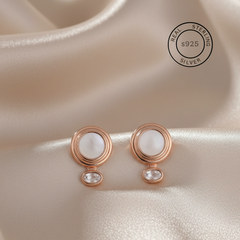 Rose gold earrings with a central MOP on a beige fabric background, featuring a 'Real Sterling Silver' stamp.