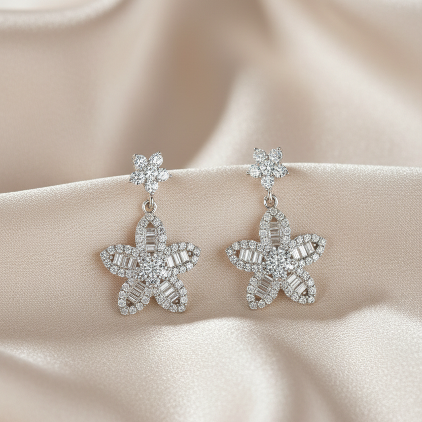 Starfish-shaped earrings with gemstones on a beige fabric background