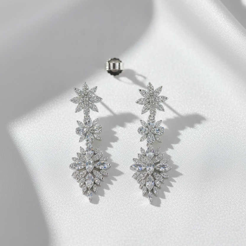 Pair of silver floral earrings on a white surface