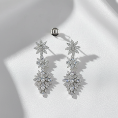 Pair of silver floral earrings on a white surface