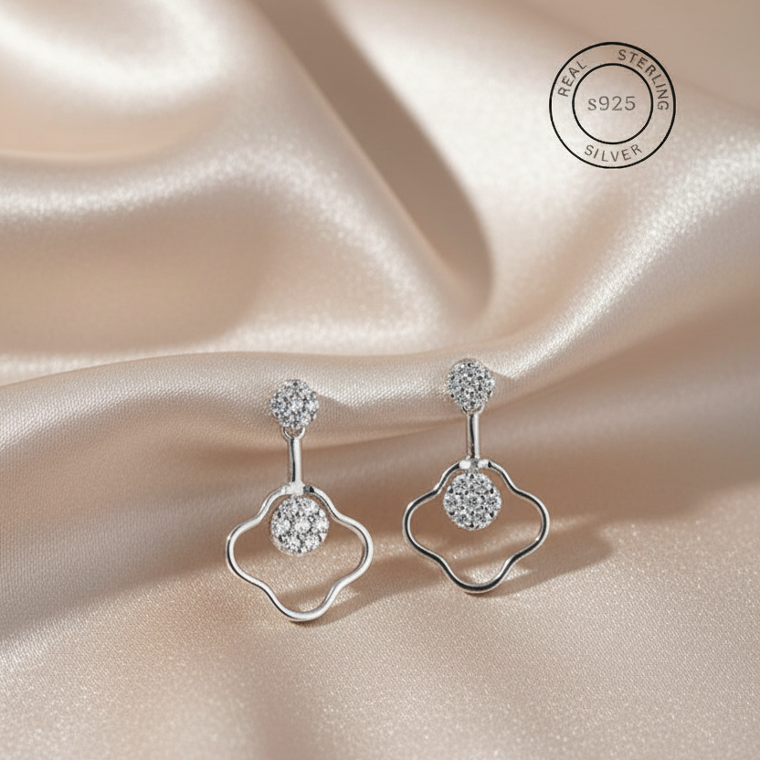 Silver earrings with gemstones on a satin background, featuring a 'Real Sterling Silver' stamp.