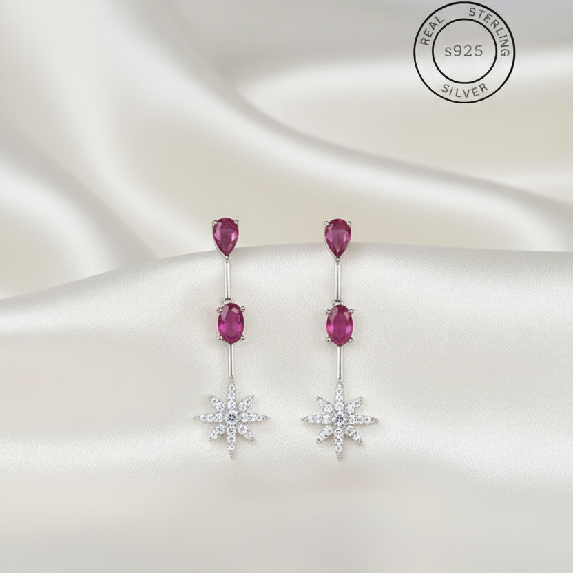 Pair of earrings with pink gemstones and star-shaped elements on a white background