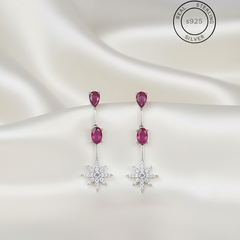 Pair of earrings with pink gemstones and star-shaped elements on a white background