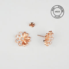Rose gold flower-shaped earrings with clear stones, featuring 'Real Sterling Silver' stamp.