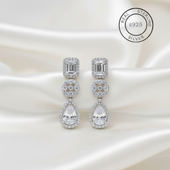 Silver earrings with AAA+ Cubic Zircons on a satin background, featuring 'Real Sterling Silver' label.