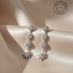 Silver earrings with star designs on a beige fabric background, featuring '925 Sterling Silver' stamp.