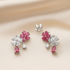 Pair of earrings with pink gemstones and silver accents on a beige background