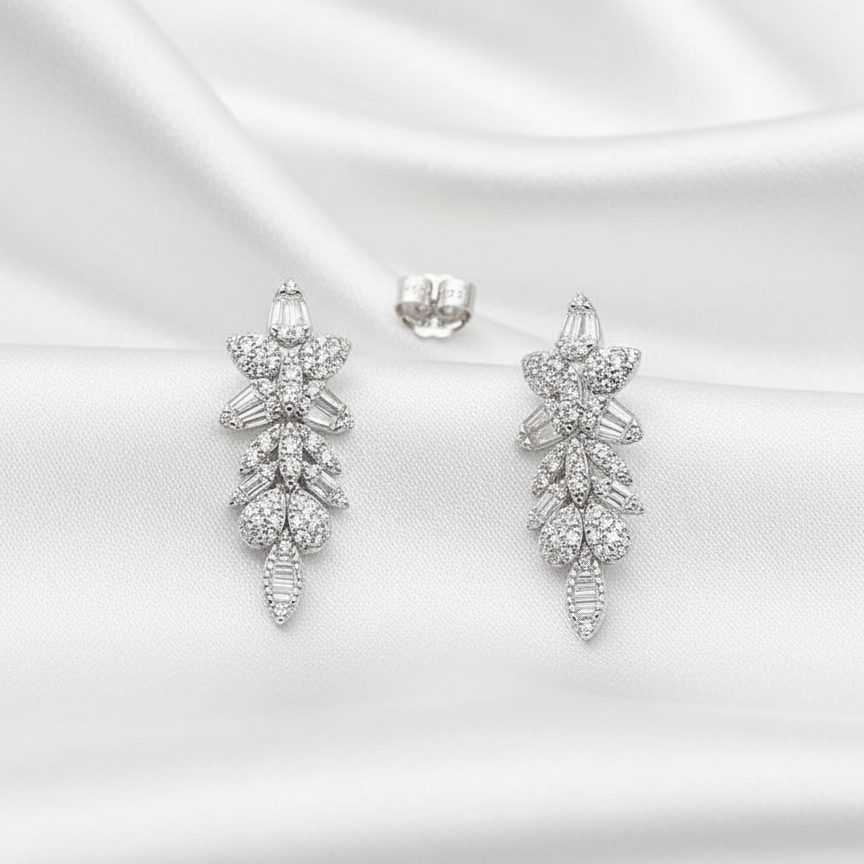 Pair of silver earrings on a white satin background