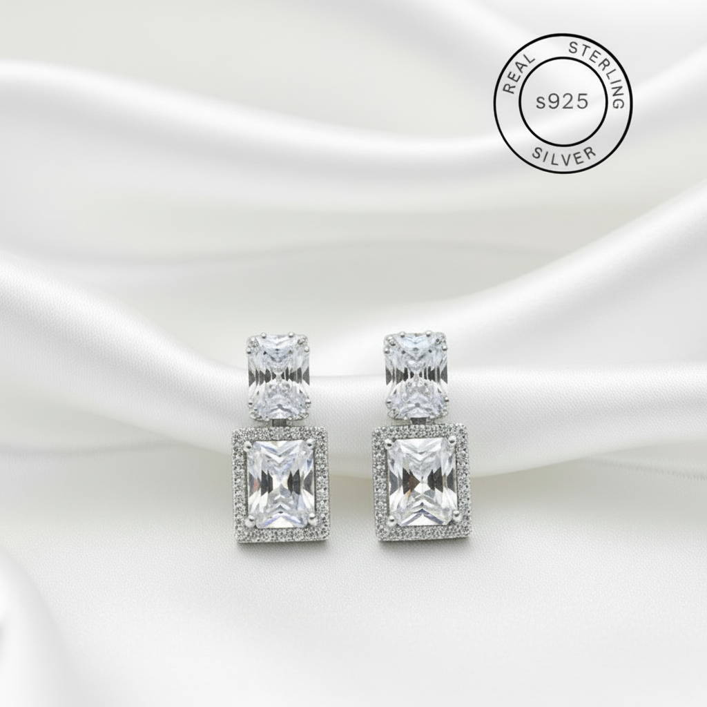 Silver earrings with clear zircon stones on a white background, featuring 'Real Sterling Silver' label.