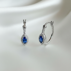 Pair of silver earrings with blue gemstones on a white background