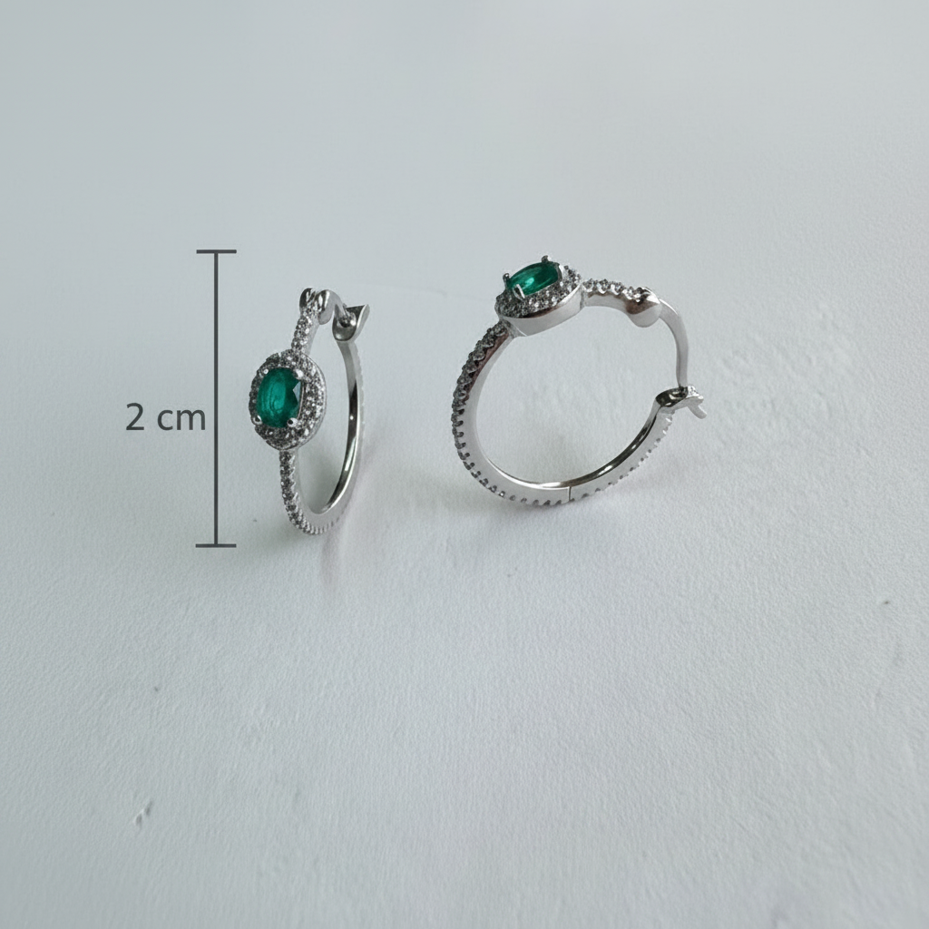 Silver hoop earrings with green gemstones on a light gray background