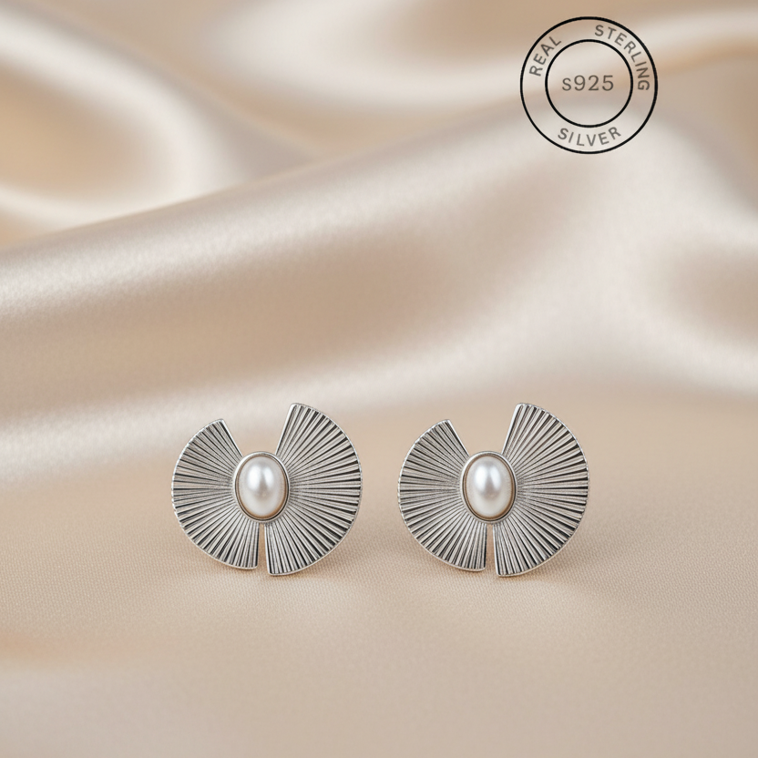 Silver earrings with pearl center on a satin background, featuring 'Real Sterling Silver' 925 stamp.
