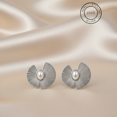 Silver earrings with pearl center on a satin background, featuring 'Real Sterling Silver' 925 stamp.