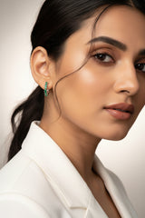 Close-up of a woman wearing green earrings with a neutral background