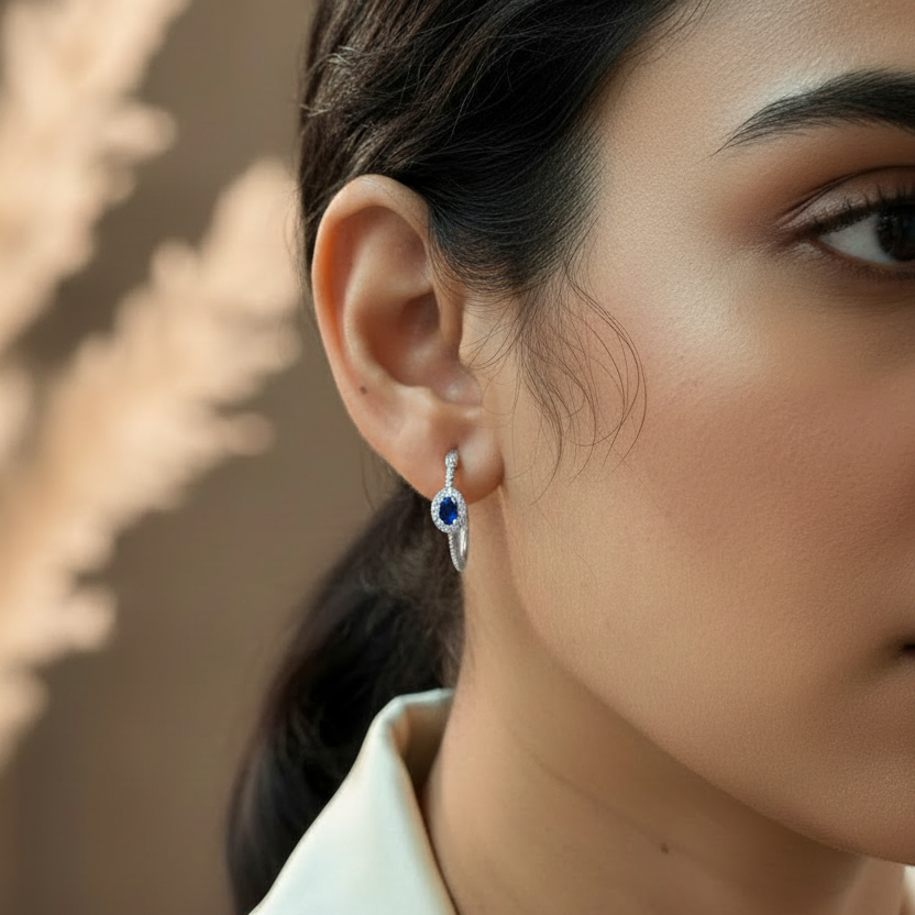 Close-up of a woman wearing a silver earring with a blue gemstone 